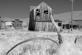 Weathered wheel rim and buildings at Bodie-bw1 6-8-07