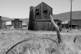 Weathered wheel rim and buildings at Bodie-bw2 6-8-07